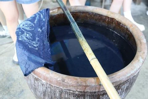 In the traditional cloth dyeing process, an old pot of indigo water is plac.. Stock Photos