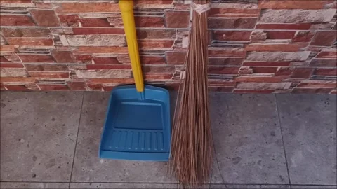 Traditional Coconut Leaf Broom and Blue Plastic Dustpan on Tile Stock Footage 331914061