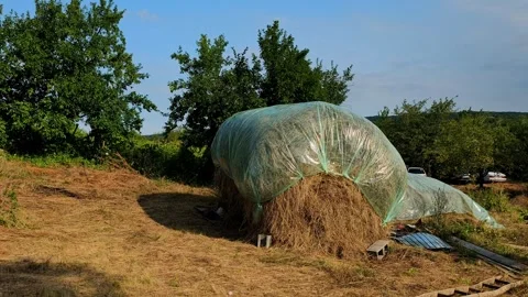 Traditional Covered Haystack Protected with Plastic Tarp in Rural Village Vídeo Stock 342113122