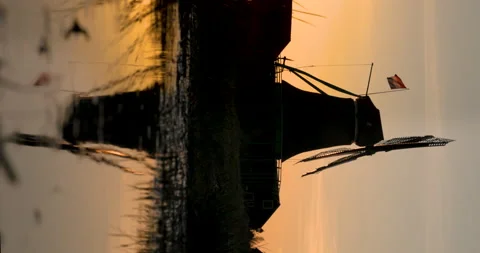 Traditional Dutch windmill reflected in calm water during a peaceful sunset. Stock Footage 304549623