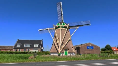 Traditional Dutch windmill with rotating sails against a clear blue summer sk Stock Footage 340229694