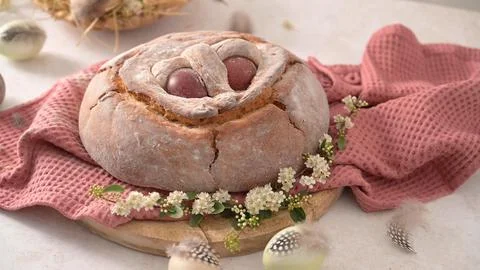 Traditional Easter bread with red eggs on a wooden board with pink cloth Stock Photos