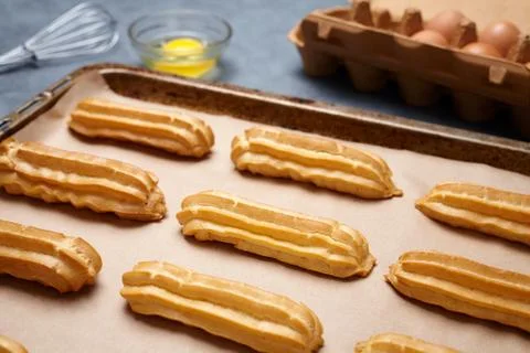 Traditional eclairs or profiterole preparing with eggs on baking sheet Stock Photos