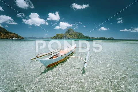 Traditional filippino fishing boat in shallow water lagoon at El Nido bay Stock Photos