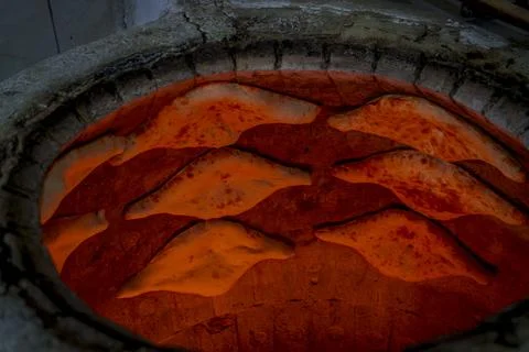 Traditional Georgian bread baking inside hot tone clay oven Stock Photos