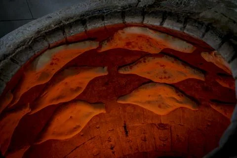 Traditional Georgian bread baking inside hot tone clay oven Stock Photos
