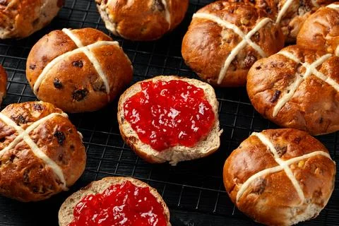 Traditional Hot Cross Buns, Easter Sweet Spiced Rolls with Dried Fruit, Straw Foto stock
