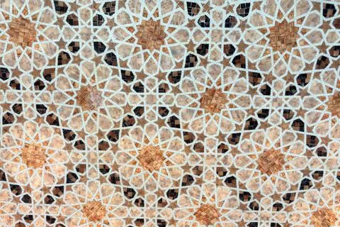Traditional Islamic geometric mosaic pattern featuring floral motifs in warm Stock Photos