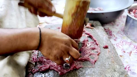 Traditional Meat Preparation by Beating Meat on Stone Stockbeeldmateriaal 339530975