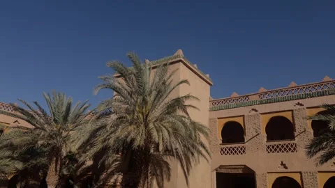 Traditional Moroccan mud brick building with palm trees and arched facade clear 库存影片 335962623