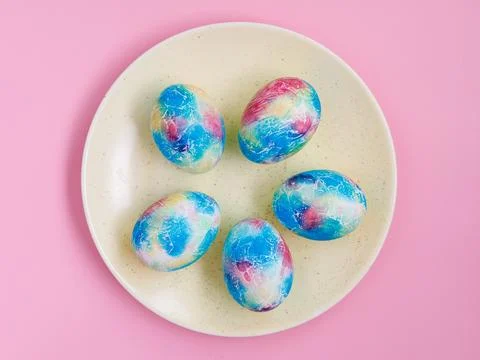 Traditional multicolored easter eggs painted like Earth on plate on pink Stock Photos