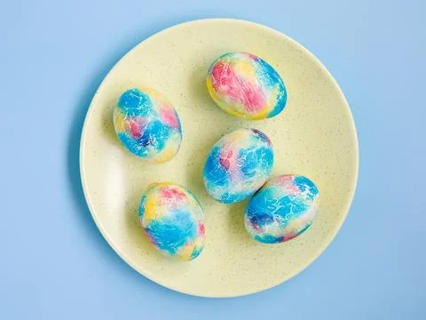 Traditional multicolored easter eggs painted like Earth on plate on blue Stock Photos