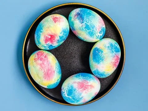 Traditional multicolored easter eggs painted like Earth on black plate on blue Stock Photos