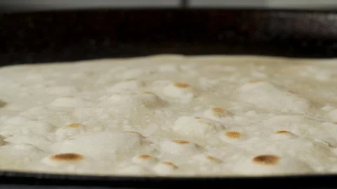 Traditional pita bread inflates with the bubble on the pan Stock Footage 127411920