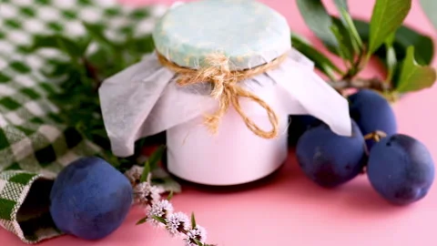Traditional plum jam in rustic jar with fresh fruit on pink background Stock Footage 342520674