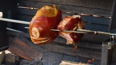 Traditional Pork Knuckle Rotating on Spit Over Wood Fire Grill Stock Footage 321509254