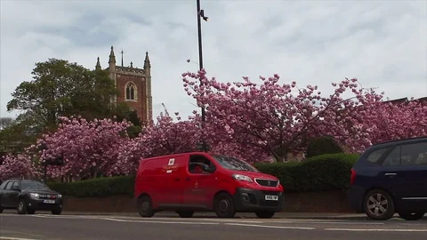 Traditional red British Post Office van drives passed English Church 動画素材 74385765