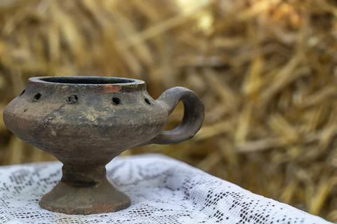 Traditional rustic ceramic vessel with handle on white lace cloth against w.. Stockfoto's
