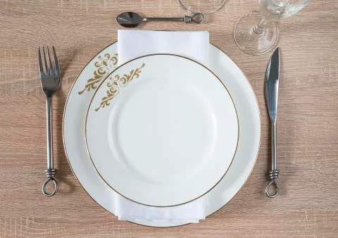 Traditional table setting. Two white plates, napkin, forged knife, fork and s Stock Photos