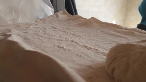 Traditional Turkish flatbread dough being rolled with a wooden rolling pin. Stock Footage 342599684