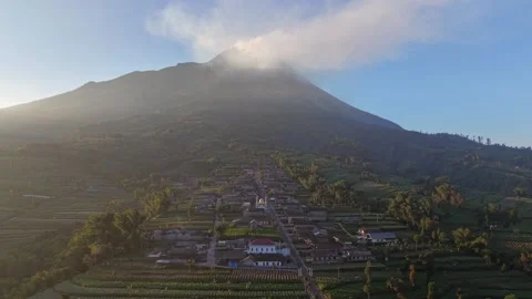 Traditional village at the base of Mount Merapi under glowing clouds. Stock Footage 338428429