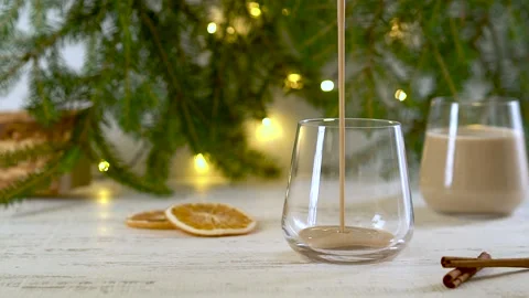 Traditional winter alcoholic eggnog cocktail pouring into a glass. Slow motion. Stock Footage