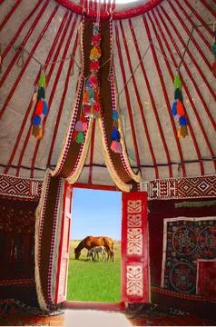 Traditional yurt interior with open door view of horses grazing outside Stock Photos