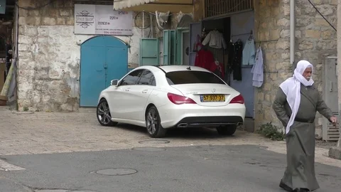 A traditionally dressed senior Druze man walks down the street in Pekiin, Israel Видео 83668633