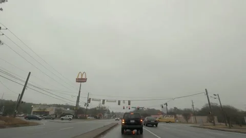 Traffic and a 4 way intersection McDonalds and busy morning traffic in the ra Stock Footage 147840651