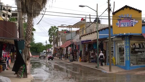 Traffic and pedestrians passing through a wet street in cabo after a storm Stock Footage 248477325