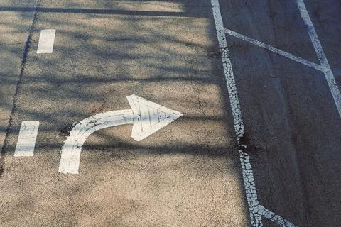 Traffic arrow indicating a right turn on a road with shadows and markings d.. Stock Photos