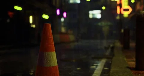 Traffic cone placed on a wet city street at night during rain Stock Illustration