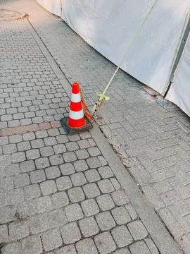 Traffic Cone Securing Tent Strap on Urban Sidewalk 写真素材