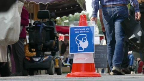 Traffic cone with sign Use face mask on a weekly market, mask requirement, Ge Stock Footage 139128083