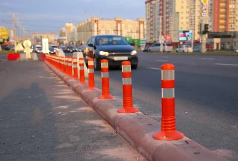 Traffic cones are placed along the side of the road in a city area while cars Stock Photos