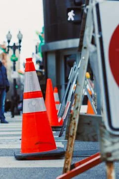 Traffic cones mark a construction site on a busy street in the city during .. Stock Photos