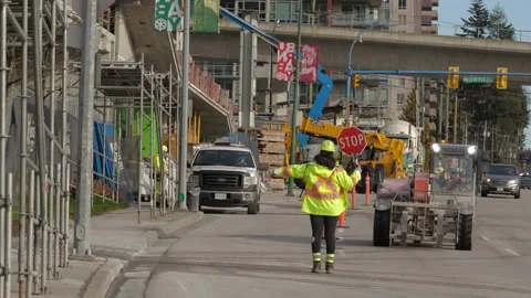 Traffic control person directing construction vehicle on the street. Video stock 147964928