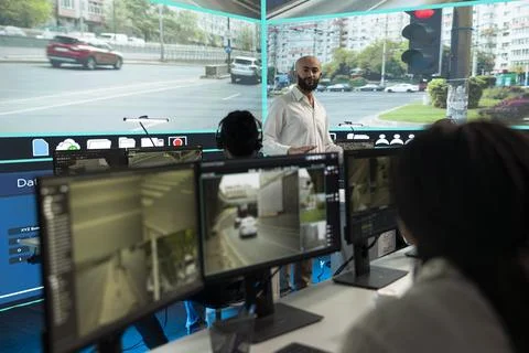 Traffic control room manager talking with seated operators, planning tasks Stock Photos