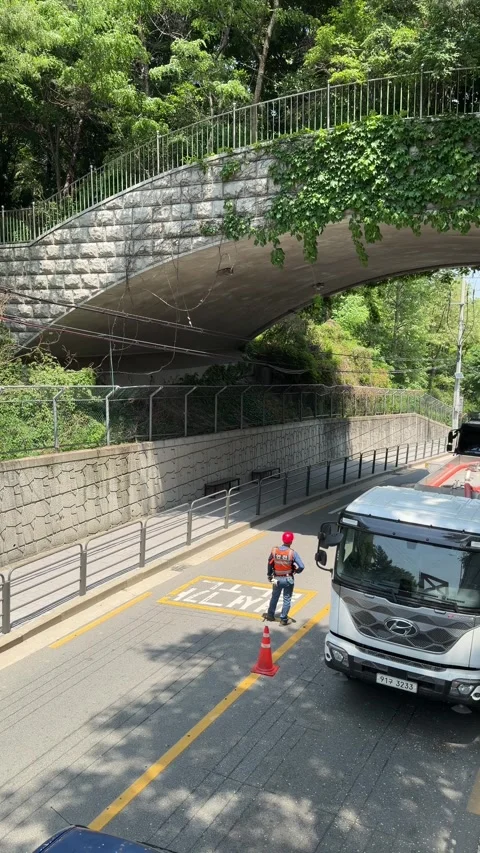 Traffic Control Worker Directing a Construction Truck Under an Overpass Stock Footage 340410024