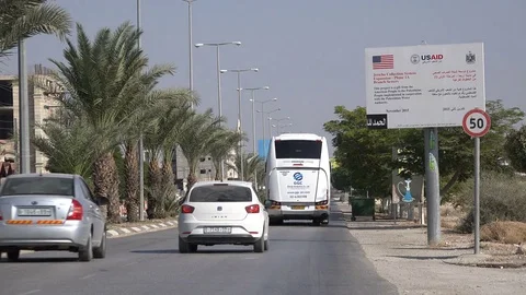 Traffic drives into Jericho past a USAID sign, in the West Bank Stock Footage