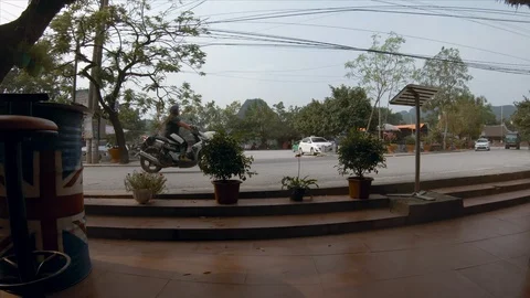 Traffic drives through the main road of Tam Coc next to the river Stock Footage 119089492