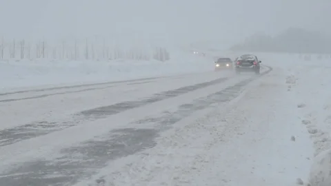 Traffic driving along freeway during intense snow storm Stock Footage 70723101