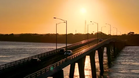 Traffic driving on bridge over ocean at sunset 스톡 동영상 259021380