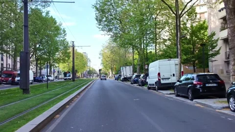 Traffic driving through a tree-lined boulevard in Paris suburbs with tramway Stock Footage 337137388