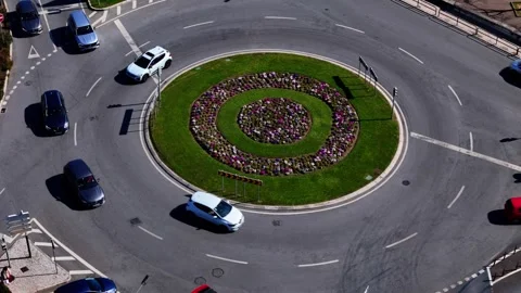 Traffic flows around a roundabout with floral design in urban area Stock Footage 302905159