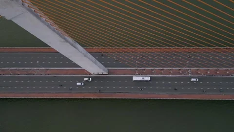 Traffic flows smoothly over modern bridge with orange cables during sunset Stock Footage 309739317
