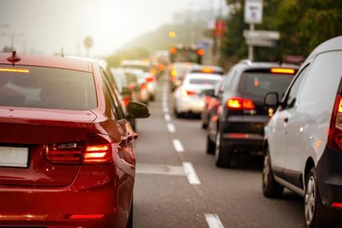Traffic jam in a city with long queue of cars waiting on a road at sunset Stock Photos