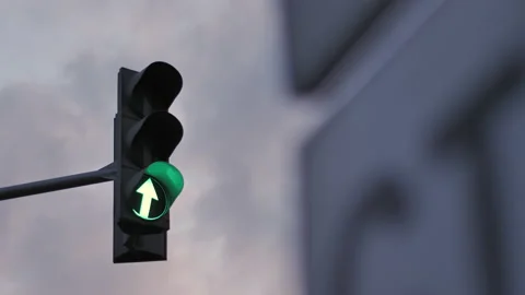 A traffic light against a cloudy sky is lit in green, orange and red. Arrow Stock Footage 141572103