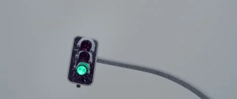 Traffic light changes color under snowstorm Stock Footage 148390350