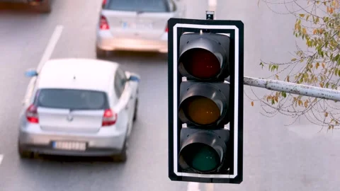 Traffic light changes from green to red, cars passing in the background Video stock 259425465